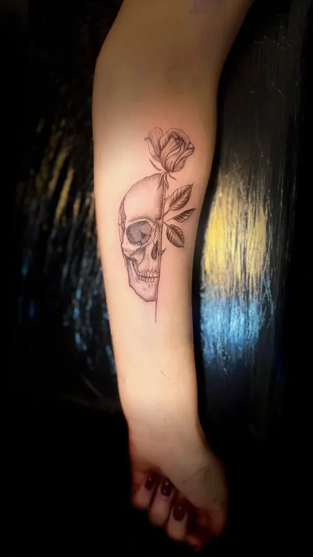 Tatuaje fine line de calavera con rosa en el antebrazo