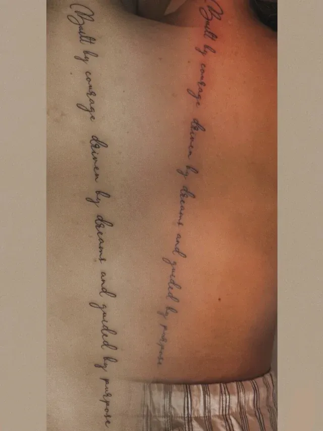 Tatuaje lettering de frase en caligrafía a lo largo de la columna