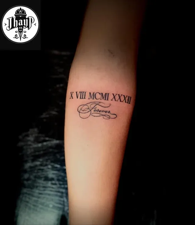 Tatuaje de fecha en números romanos en el antebrazo