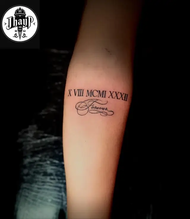 Tatuaje de fecha en números romanos en el antebrazo