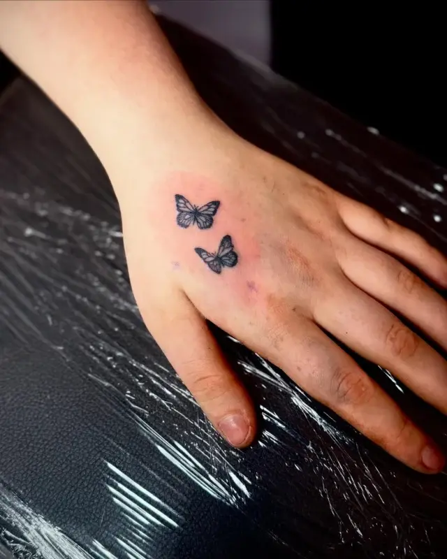 Tatuaje pequeño de mariposas en la mano