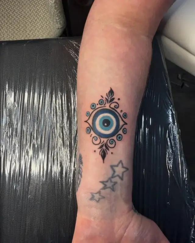 Tatuaje pequeño de ojo turco con estrellas en el antebrazo