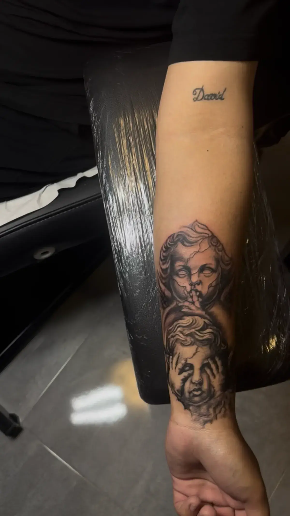 Tatuaje realista de querubines en negro y gris en el antebrazo
